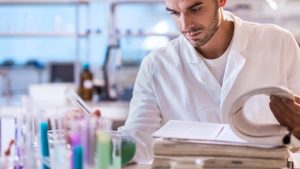 scientist in a lab coat analyzing test tubes and research documents in a laboratory setting