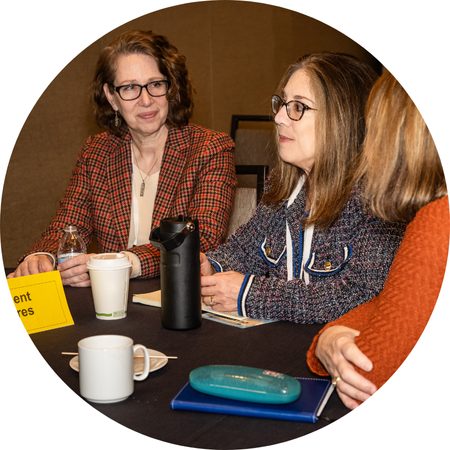 Three women sat at a table conversing